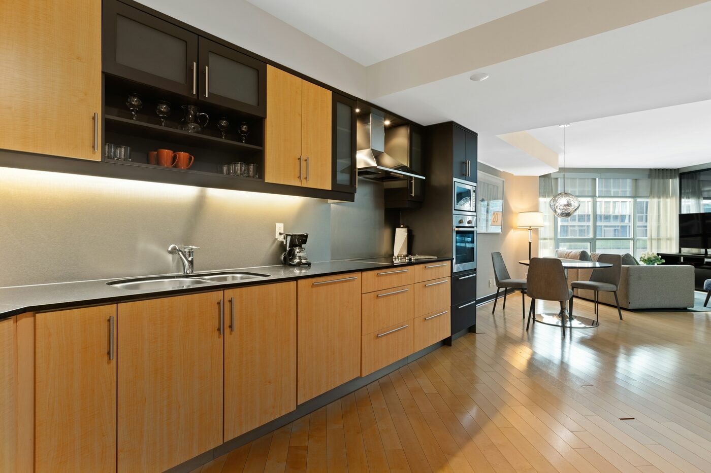 Finished two-tone kitchen with light maple lower cabinets and dark upper cabinets, open to a dining and living area.